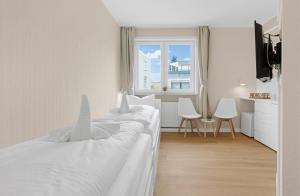 a white bedroom with a bed and a window at Auszeit Borkum zentral & strandnah in Borkum