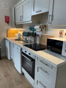 a kitchen with white cabinets and a black stove top oven at Superb Location 3 MIN TO RDS, AVIVA, D4 2 BED APARTMENT in Dublin
