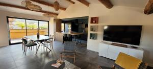 a living room with a large television and a table and chairs at L'ENTRE POTES - Maison de caractère climatisée avec garage in Villedieu