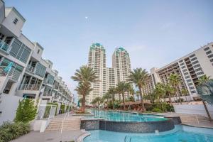 a swimming pool with palm trees and tall buildings at 1901 Sapphire Beachfront 3 Bedroom Condo in South Padre Island