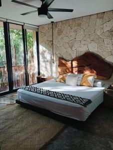 a bedroom with a large bed with a stone wall at Agua & Selva luxury Jungle loft in Tulum +51 photos