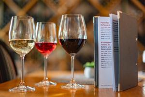 drie wijnglazen zittend op een tafel naast een boek bij Hotel Bonvino Badacsony in Badacsonytomaj