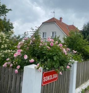 einen Zaun mit rosa Rosen und ein Schild vor einem Haus in der Unterkunft Prvorepublikový dům se zahradou in Podivín