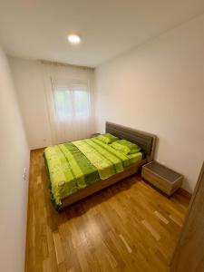 a bedroom with a bed with a green comforter at Cozy 1 bedroom APT with free parking in Podgorica