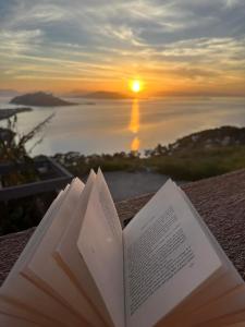 a book on a table with a sunset in the background at La Casa Del Sol Villa in Aegenitissa