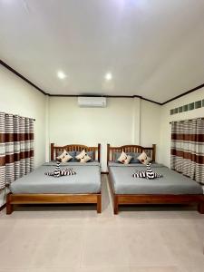 dos camas sentadas una al lado de la otra en una habitación en บ้านคุณโต้ง เชียงคาน BaanKhunTong ChiangKhan, en Chiang Khan