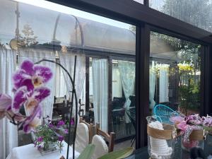 フィウミチーノにあるユーロ ハウス イン エアポートのガラスドアとテーブルの上に花を飾ったコンサバトリー