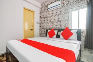 1 dormitorio con 1 cama grande con almohadas rojas en OYO Oxy Rudra Inn, en Ranchi