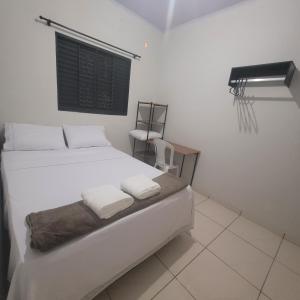 a bedroom with a white bed and a window at Casa Limoeiro in Primavera do Leste
