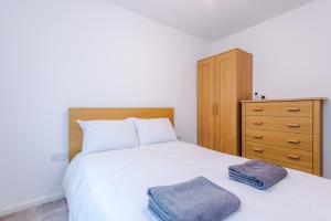 een slaapkamer met een wit bed en een houten dressoir bij Cozy 1BR Home in Vibrant Manchester Free Parking - Fast Internet in Manchester