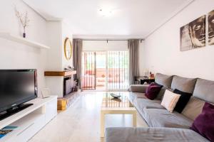 Una sala de estar con un sofá y un televisor de pantalla plana. en Apartamento en Marbella Guadalmina primera linea de campo de golf Los Cartujanos, en Marbella