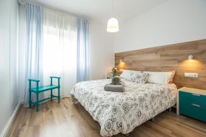 - une chambre avec un lit et une chaise bleue dans l'établissement CARTAGENAFLATS, Piso Moderno 3 Dormitorios, Cartagena Center, à Carthagène