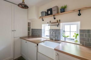 a kitchen with white cabinets and a sink and a window at Parea Living - Spacious North London House with Big Garden in London