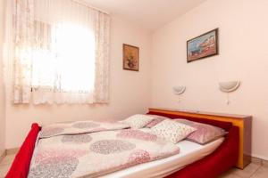 - une chambre avec un lit doté d'une tête de lit rouge et d'une fenêtre dans l'établissement Beautiful Apt Barby near Queen Beach, à Privlaka