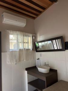 a bathroom with a white sink and a window at Coco Suites in Abraão