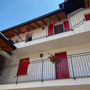a building with red doors and balconies with potted plants at La Volpe Rossa Rooms and Apartments in San Felice del Benaco
