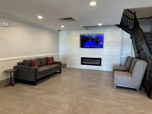 a living room with a couch and a tv on a wall at Hawthorn Extended Stay by Wyndham Hobbs in Hobbs
