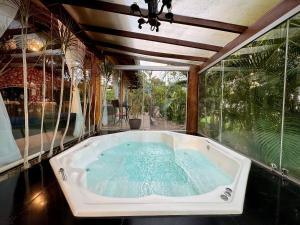 uma banheira num quarto com uma grande janela em Rancho Flor de Iris - Lago Corumbá IV em Alexânia