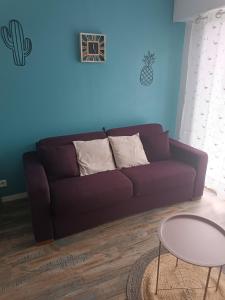 un sofá púrpura en una sala de estar con mesa en studio Cosy proche hyper centre, en Quimper