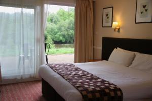 a hotel room with a bed and a large window at Inn On The Lake in Gravesend
