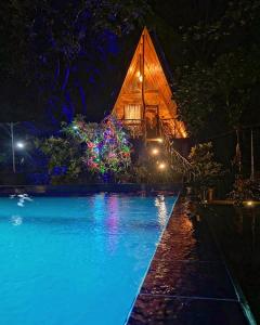 a resort with a swimming pool at night at Levona Garden Resort in Habarana