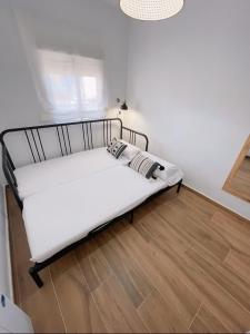 een wit bed in een kamer met een houten vloer bij Apartamento Boho Chic in Denia