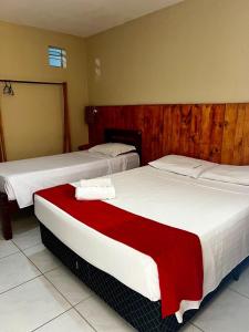 2 camas en una habitación de hotel con sábanas blancas y rojas en El Dorado Hotel Fortaleza, en Fortaleza