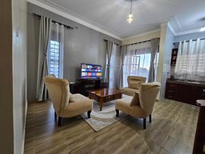 a living room with chairs and a tv and a table at Orgonite SmartHomes in Kampala