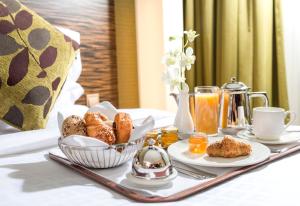 a breakfast tray with pastries and orange juice on a bed at Atana Hotel in Dubai
