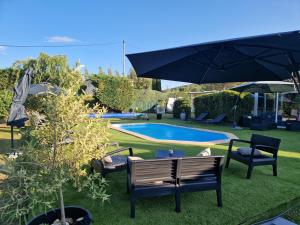 einen Garten mit Stühlen, einem Sonnenschirm und einem Pool in der Unterkunft L'étape Provencale in Cabriès
