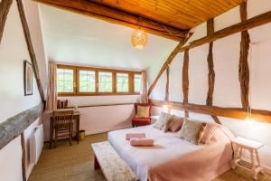 um quarto com uma cama num quarto com tectos em madeira em 2 maisons dans parc de 0,7 ha à 1h30 de Paris em Triguères