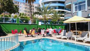 een groep mensen die rond een tafel bij een zwembad zitten bij Bay Luna Beach hotel in Alanya