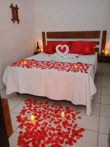 ein Schlafzimmer mit einem Bett mit roten Rosen auf dem Boden in der Unterkunft HOTELARE Pousada Bóra Morá in Ubatuba