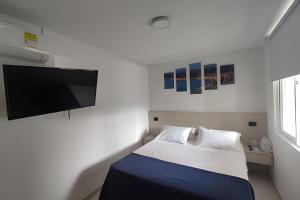 a bedroom with a bed and a flat screen tv at Amplios Apartamentos San Fernando Cerca a Centros Médicos in Cali