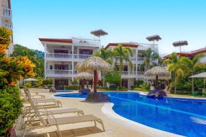 um resort com uma piscina com cadeiras e guarda-sóis em La Paloma Blanca B1 em Jacó