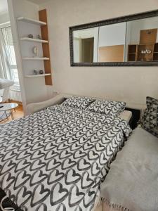uma cama com um edredão preto e branco e um espelho em Belville City apartment em Belgrado