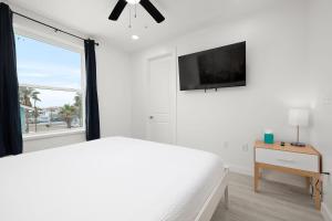 ein weißes Schlafzimmer mit einem weißen Bett und einem Fenster in der Unterkunft Marisol Condo 301 in South Padre Island