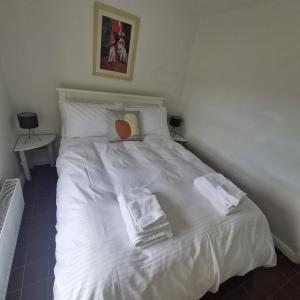 a bed with white sheets and towels on it at Coastal Charm Cottage in Knockfin Cross Roads
