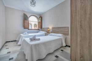 twee bedden in een witte kamer met een raam bij Casa con patio María Auxiliadora in Córdoba