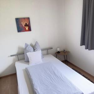 a bedroom with a white bed and a picture on the wall at Alpenblick Schattwald in Schattwald