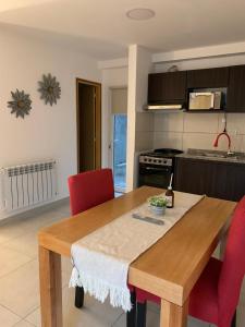 cocina con mesa de madera y sillas rojas en Bouchard-Ushuaia Flat, en Ushuaia
