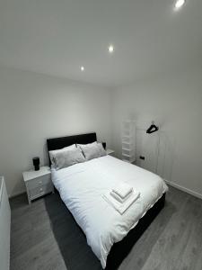 a bedroom with a large bed with white sheets at Luxury 2 Bed Apartment, Sleeps 6 with Sofa bed, Close to Sale Tram Station in Sale