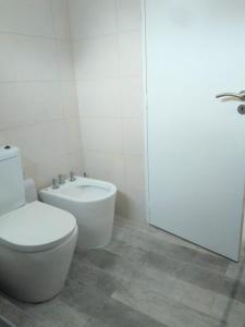 a white bathroom with a toilet and a sink at Village de Mar in Monte Hermoso +13 photos