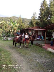 un grupo de personas montando caballos delante de una casa en Tarragona Hostal, en Santa Rosa de Cabal