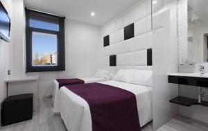 a white bedroom with a bed and a sink at Hoteles Urbanos N Avenida de España in Fuenlabrada