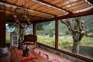 Habitación con ventana grande con mesa y sillas. en Hacienda Hostería Dos Chorreras, en Cuenca