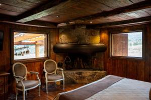 a bedroom with a bed and two chairs in front of a fireplace at Hacienda Hostería Dos Chorreras in Cuenca