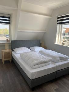 two white beds in a bedroom with two windows at Beach Dream 3C in Petten