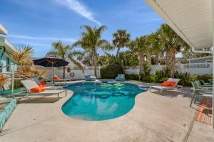 a swimming pool with chairs and an umbrella at Walk to Beach, Heated Pool, Dog-Friendly, Firepit in Daytona Beach