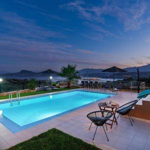 a swimming pool with two chairs and a table at Villa Roula 3BR Seaview Villa in Chania in Stérnai